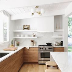 a kitchen with white counter tops and wooden cabinets next to a stove top oven under a window