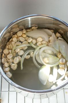 onions and chickpeas are being cooked in a pot on the stove with water