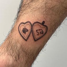 two heart shaped tattoos on the wrist, one with a dog and cat in it