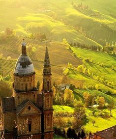 an aerial view of a church in the middle of a green valley with rolling hills