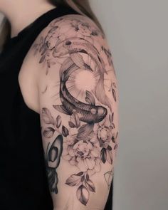 a woman's arm with flowers and a fish tattoo on her left shoulder, in black and white