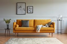 a living room with a yellow couch and two framed pictures on the wall above it