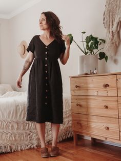 a woman standing in front of a bed with a potted plant on top of it