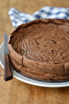 a chocolate cake sitting on top of a white plate with a knife next to it