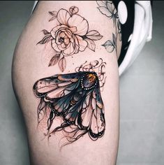 a woman's thigh with a butterfly tattoo on it and flowers around the thighs