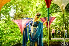 a woman dressed as a fairy standing in the woods