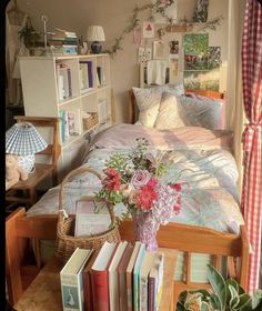 a room with a bed, books and flowers in it