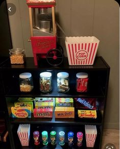 a shelf filled with snacks and popcorn on top of a wooden floor next to a wall