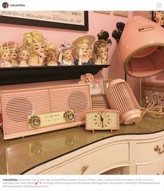 a pink radio sitting on top of a desk next to a clock and other items