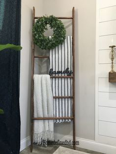 an old ladder is used as a towel rack for towels and wreaths in the bathroom