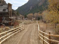 a dirt road that is next to a wooden fence