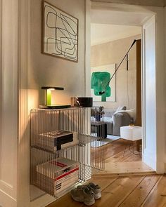 a living room filled with furniture and a metal shelf next to a lamp on top of a hard wood floor