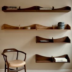 two shelves with books and bowls on them in a room that has a chair next to it