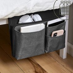 an open storage bag on the floor next to a bed with two cell phones in it