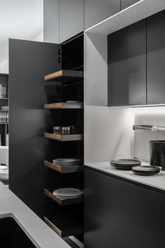 a black and white kitchen with plates on the counter top in front of cabinets that are open