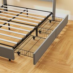 a bed frame with metal rails on top of it in a room that has hardwood floors