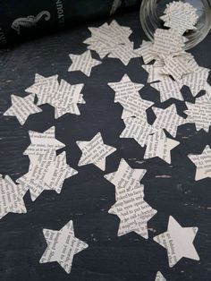 some paper stars are laying on the ground next to a glass jar with writing on it