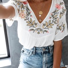 a woman wearing a white top and denim shorts