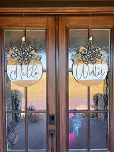 two double doors with wreaths and bow on them that say hello winter in front of the door