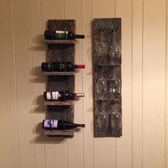 two wine glasses are hanging on the wall next to a shelf with bottles and glasses