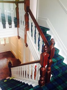 there is a blue and green carpeted stair case next to the white handrail