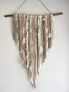 a wall hanging made out of fabric and wood sticks with yarn on the ends,