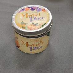 a jar of market place marmalade sits on a gray tablecloth next to an orange slice