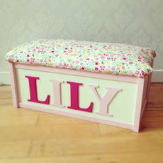 a toy bench with the word lilly on it's back and flowers in pink