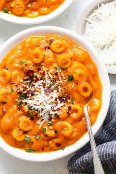 two bowls filled with pasta and cheese on top of white rice next to silver spoons