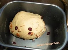 an uncooked doughnut in a metal pan with raisins on it