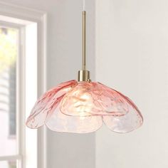 a pink glass light hanging from a ceiling fixture in a room with white walls and windows