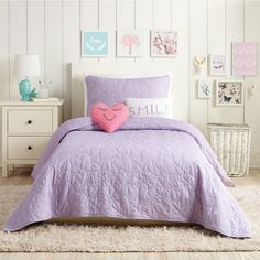 a bed with purple bedspread and pink heart shaped pillow on top of it