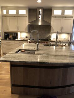 a large kitchen with an island in the middle and stainless steel appliances on both sides