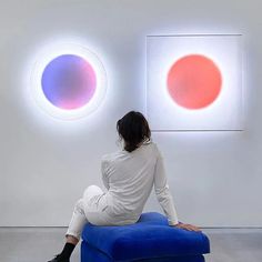 a woman sitting on top of a blue chair in front of two circles that are colored