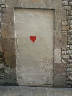 a red heart is painted on the side of a stone building in an alleyway