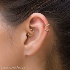 a woman's ear is shown with two small gold hoops