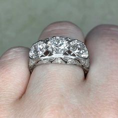 a woman's hand holding a three stone diamond ring