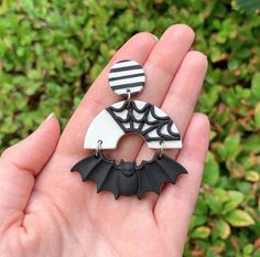 a hand holding two earrings with bats on them