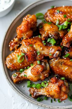 a white plate topped with chicken wings covered in sauce