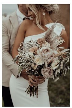 a bride and groom standing close to each other in front of the ocean holding their bouquet