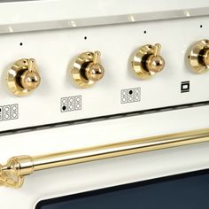 a white stove with gold knobs and brass handles