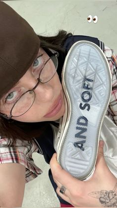 a woman with glasses holding up a shoe