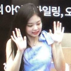 a young woman is waving her hands in front of a tv screen with the korean language on it