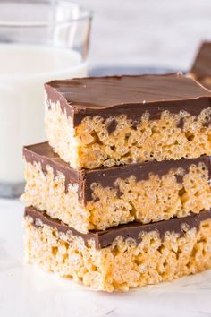 three pieces of peanut butter rice krispy treats stacked on top of each other next to a glass of milk