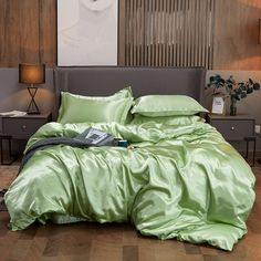 a bed with green sheets and pillows on top of it in front of a painting