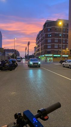 a city street at dusk with cars and motorcycles