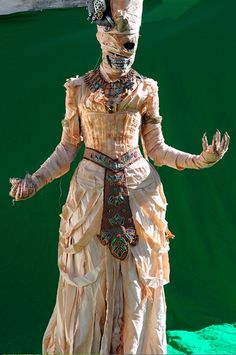 a woman dressed in an elaborate dress and headdress, with hands outstretched to the side