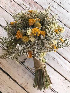 a bouquet of yellow and white flowers sitting on top of a wooden table