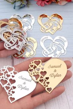 four different types of wedding rings with names and hearts on the front, two are gold, one is silver