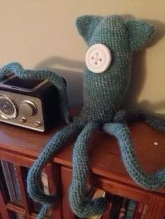 an octopus stuffed animal sitting on top of a wooden shelf next to a camera and bookcase